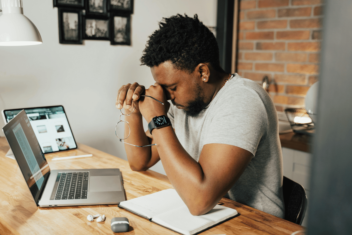 a man sitting at his computer holding a hand to his face