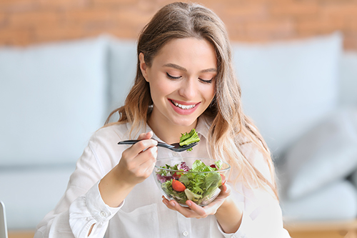 Woman eating healthy vegetable salad in office