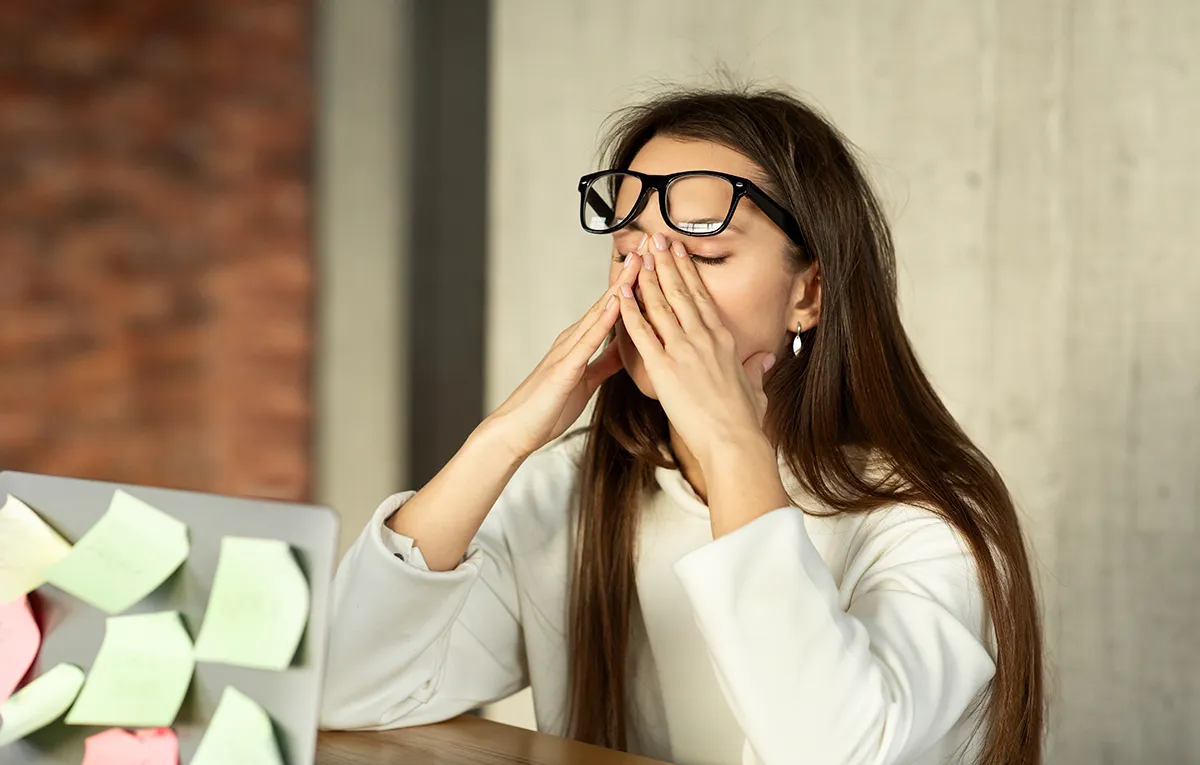 a young woman rubbing her eyes due to dry eyes