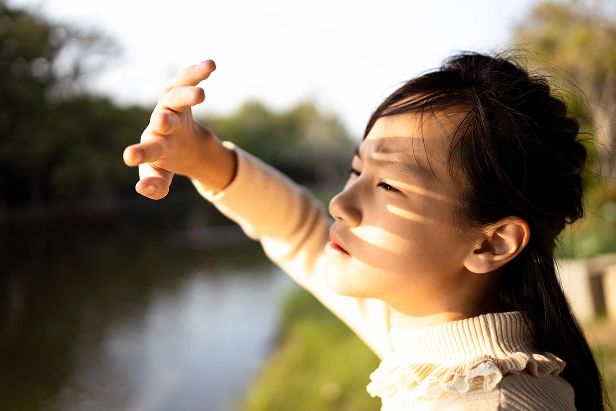 a woman covering her face to protect her eyes from bright sunlight
