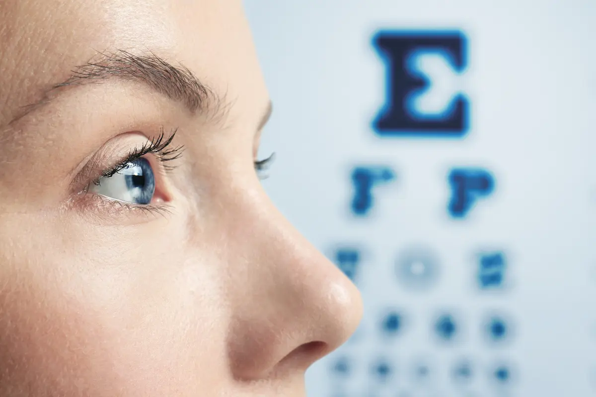Close-up of woman's eyes with blurry Snellen chart in background